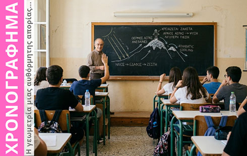 Ένας καθηγητής μαθηματικών με κιμωλία στο χέρι σχεδιάζει ένα βουνό στον σχολικό πίνακα, εξηγώντας μια απορία σε μια τάξη γεμάτη με εφήβους μαθητές.